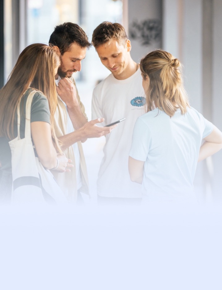 Vier Personen lösen gemeinsam eine Aufgabe auf dem Smartphone